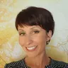 Olivia Gamboni, cheveux bruns courts, grand sourire, devant un décor d’arbres dorés